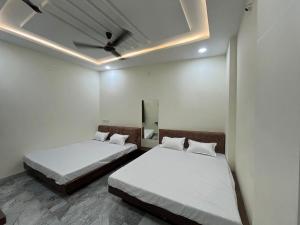 two beds in a room with white walls and a ceiling at Maheshwari Homes in Ujjain