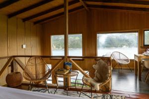 a room with chairs and a table and windows at Pumillahue Lodge cabaña matrimonial in Ancud