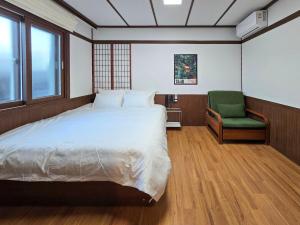 - une chambre avec un lit et une chaise verte dans l'établissement Staykor Busan, à Pusan