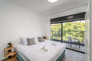 a white bedroom with a large bed and a balcony at Luxurious 3Bedroom Apartment Emek Refaim Jerusalem in Yerushalayim