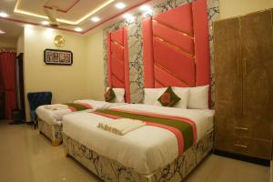 2 camas en una habitación de hotel con puertas rojas en Gold Max Hotel, en Lahore