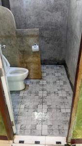 a bathroom with a toilet and a tiled floor at Turtle beach Bar 1 Bedroom in Thai Muang