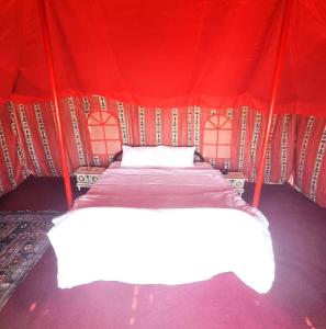 een slaapkamer met een bed in een rode tent bij Beach Moments Camp in Aḑyūḩ +6 foto's