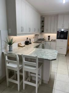 a kitchen with white cabinets and a counter with stools at Through the Window in Gqeberha +16 photos