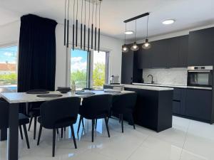 une cuisine avec une table et des chaises et une cuisine avec des armoires noires dans l'établissement Villa TEREZA Luxury Sea View Villa for Families & Romantic Getaways, à Sveti Vid-Miholjice