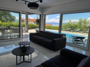 - un salon avec un canapé et une vue sur la piscine dans l'établissement Villa TEREZA Luxury Sea View Villa for Families & Romantic Getaways, à Sveti Vid-Miholjice
