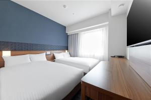 Postel nebo postele na pokoji v ubytování Sotetsu Fresa Inn Kitahama