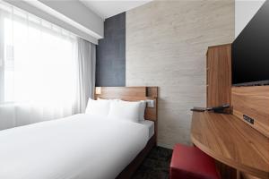 Postel nebo postele na pokoji v ubytování Sotetsu Fresa Inn Kitahama