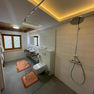 een badkamer met een toilet, 2 wastafels en een douche bij Hotel Sonnleiten in Reit im Winkl
