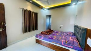 a bedroom with a bed with a purple comforter at Maa Rewa Palace in Sānāwad