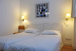 a bedroom with two beds with white sheets and a picture on the wall at Loft Vinaigriers République in Paris