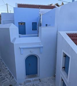 un edificio bianco con una porta blu e scale di Aleminas Rooms 2 a Sými