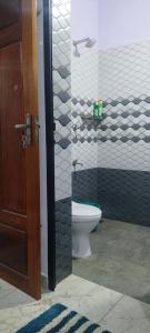 a bathroom with a toilet and a glass door at Grape Garden in Varkala