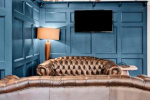 een bruine leren bank in een blauwe kamer met een televisie bij Pyes Mill Hotel Conder Green in Conder Green
