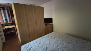 a bedroom with a bed and a cabinet and a television at WHITE ALPS Apartment in Schilpario