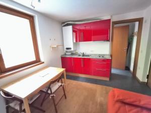 a kitchen with red cabinets and a wooden table at WHITE ALPS Apartment in Schilpario