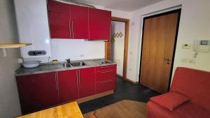 a kitchen with red cabinets and a red couch at WHITE ALPS Apartment in Schilpario
