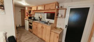 a small kitchen with wooden cabinets and a stove at Dancing Seagulls Caravan in Clacton-on-Sea