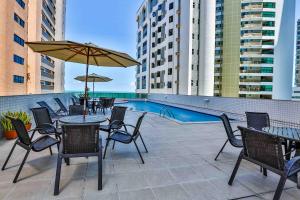 a patio with tables and chairs and a pool at Flat Beach Class Executive - Beira Mar de Boa Viagem in Recife