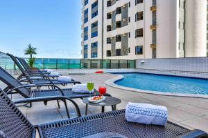a hotel patio with chairs and a swimming pool at Flat Beach Class Executive - Beira Mar de Boa Viagem in Recife