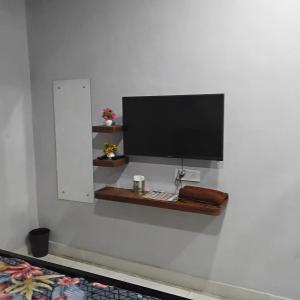 a flat screen tv on a wall with a shelf at nyagaon swimming pool in Malaut