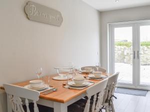 een eetkamer met een houten tafel met witte stoelen bij Crofthouse - Uk43405 in Wigtown