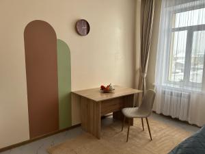 Zimmer mit einem Tisch, einem Stuhl und einem Fenster in der Unterkunft Bekarys Hotel in Astana