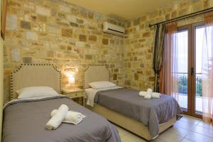 una camera da letto con due letti e un muro di pietra di Villa-Τo Petrino a Krionérion