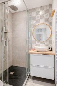 a bathroom with a shower with a sink and a mirror at Le Plein Sud in Le Grau-du-Roi