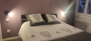 una camera da letto con un letto con lenzuola e cuscini bianchi di Gîte L'hôtellerie a Trévron