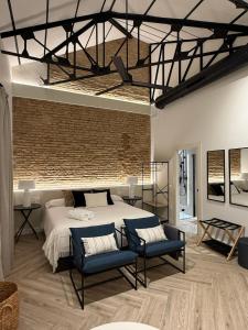 ein Schlafzimmer mit einem großen Bett und zwei blauen Stühlen in der Unterkunft Arcos de Santa Marta in Córdoba