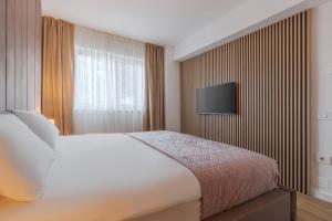 a bedroom with a bed and a television on a wall at Velour Suites in Oradea +42 photos