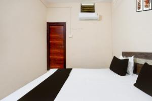 um quarto com uma cama branca e uma porta de madeira em Hotel O by OYO RASRANG em Raipur