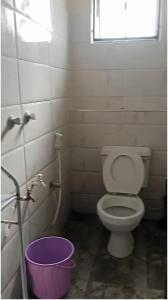 een badkamer met een toilet en een raam en een emmer bij Flynn Stays in Bamburi