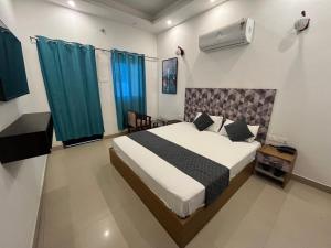 Schlafzimmer mit einem großen Bett und blauen Vorhängen in der Unterkunft Ashoka Resort in Begusarai