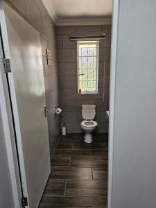 een badkamer met een toilet en een raam bij Phozi Inn in Eshowe
