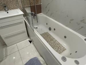 a white bathroom with a tub and a sink at Chartsworth 4 Bedrooms Spacious House in Harold Wood +44 photos