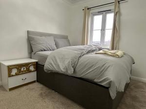a bedroom with a bed with a night stand and a window at Chartsworth 4 Bedrooms Spacious House in Harold Wood
