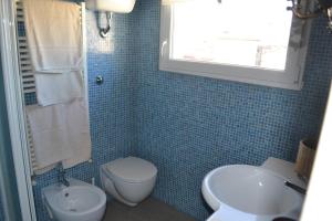 een blauw betegelde badkamer met een toilet en een wastafel bij La Dimora della Luna Appartamento Rosso in Trieste