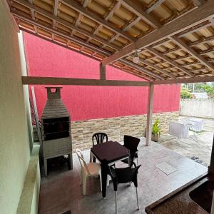 eine Terrasse mit einem Tisch und einem Holzofen in der Unterkunft Casa do Rocco in Cabo Frio