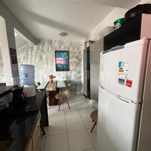 eine Küche mit einem weißen Kühlschrank und einem Tisch in der Unterkunft Casa do Rocco in Cabo Frio