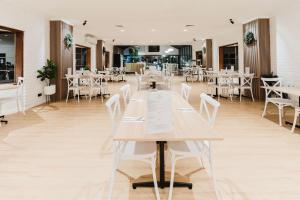 a restaurant with white tables and white chairs at Country 2 Coast Motor Inn Coffs Harbour in Coffs Harbour