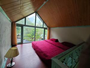 een slaapkamer met een rood bed en een groot raam bij Teji's Riverside Cottages in Kasol