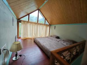 een slaapkamer met een bed in een kamer met een raam bij Teji's Riverside Cottages in Kasol