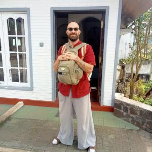 Un uomo con uno zaino davanti a una porta di Nehara Inn a Nuwara Eliya