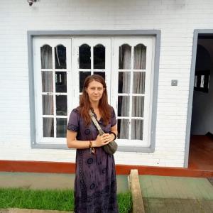 una donna con un vestito viola in piedi davanti a un edificio di Nehara Inn a Nuwara Eliya