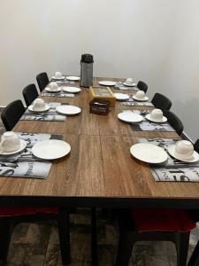 a long wooden table with chairs and plates on it at Hostal Malú in San Pedro de Atacama