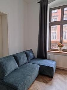 un divano blu in soggiorno con finestra di CanvasHome Apartamenty a Katowice