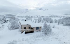 ein schneebedecktes Haus auf einem Feld in der Unterkunft Casa Hikari - Lofoten Retreat in Vestvågøya