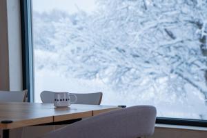 einen Tisch und Stühle vor einem Fenster mit Schnee in der Unterkunft Casa Hikari - Lofoten Retreat in Vestvågøya